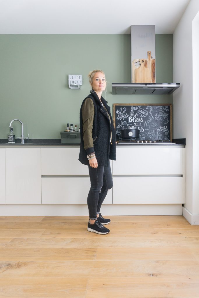 Chantal poseert in haar witte keuken met groene wand. 