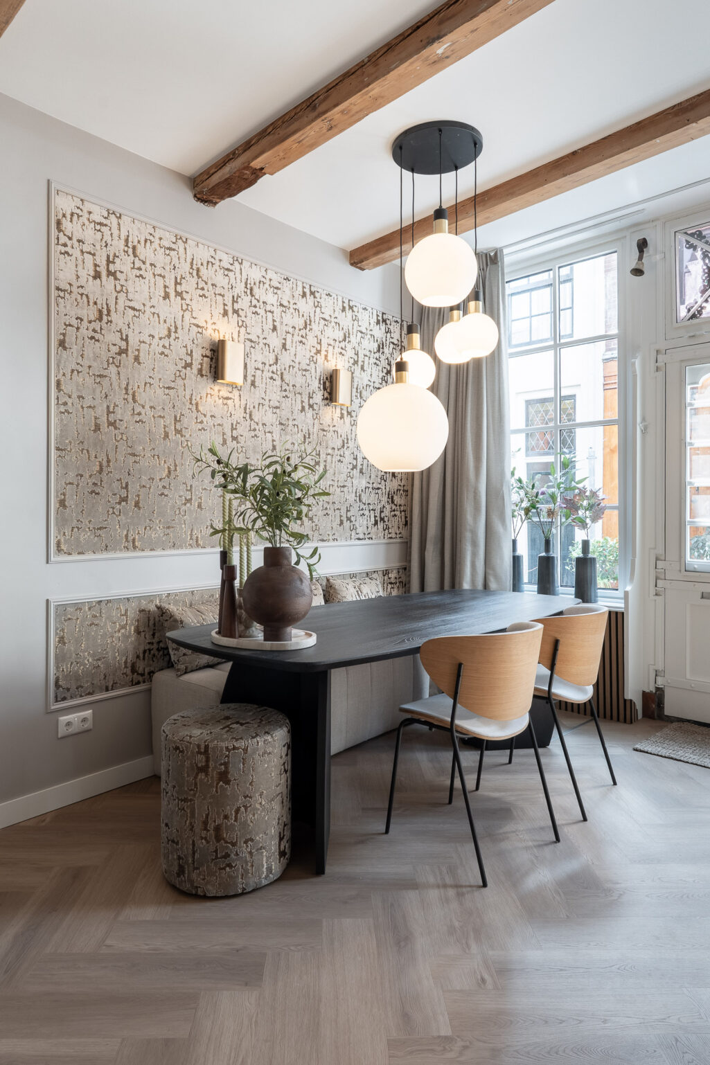 Ovalen zwarte eettafel met behang op wandpanelen.