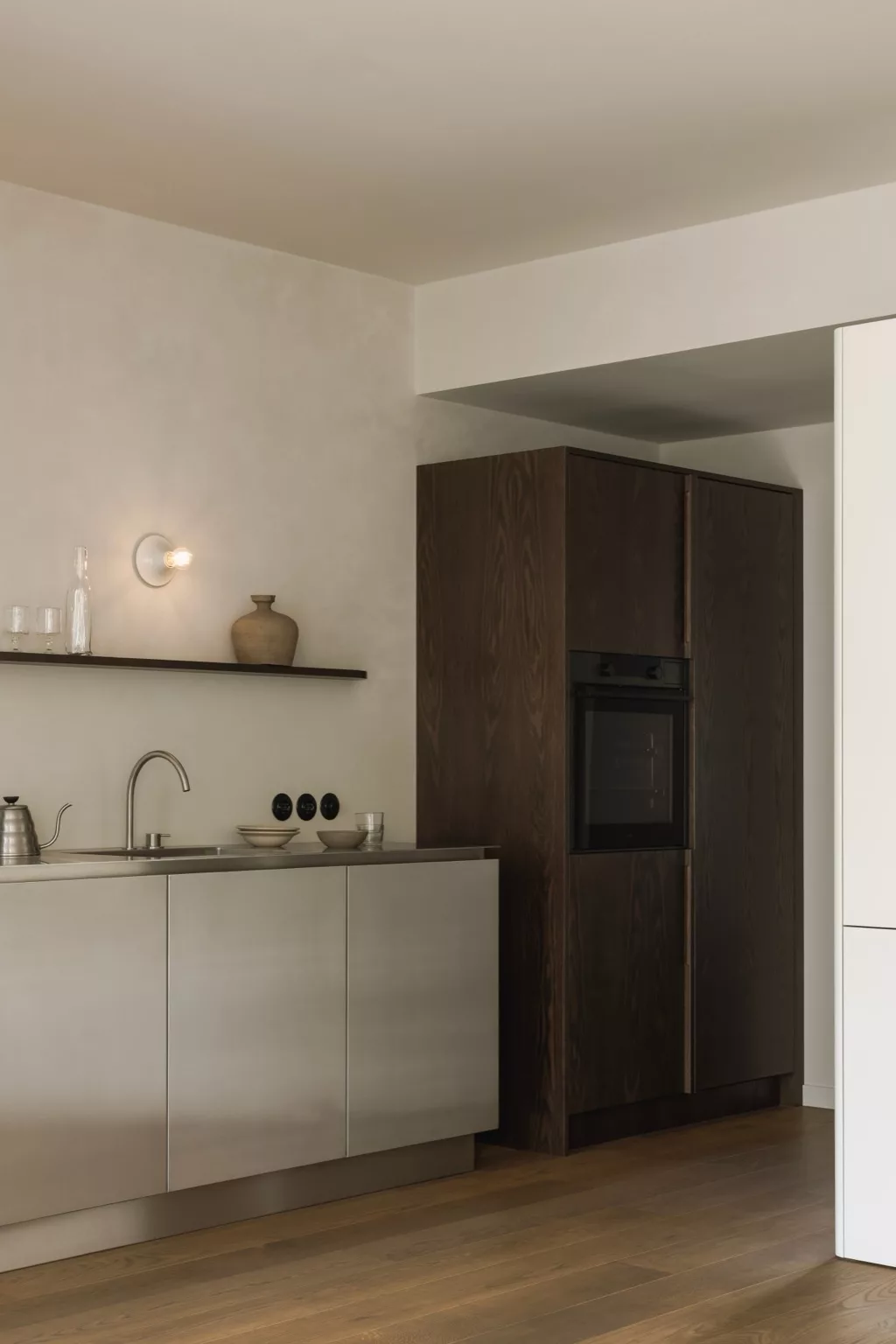 Lichte keuken, lichte wanden en keukenkasten, werkblad staal, kraan staal, donderhouten hoge kasten