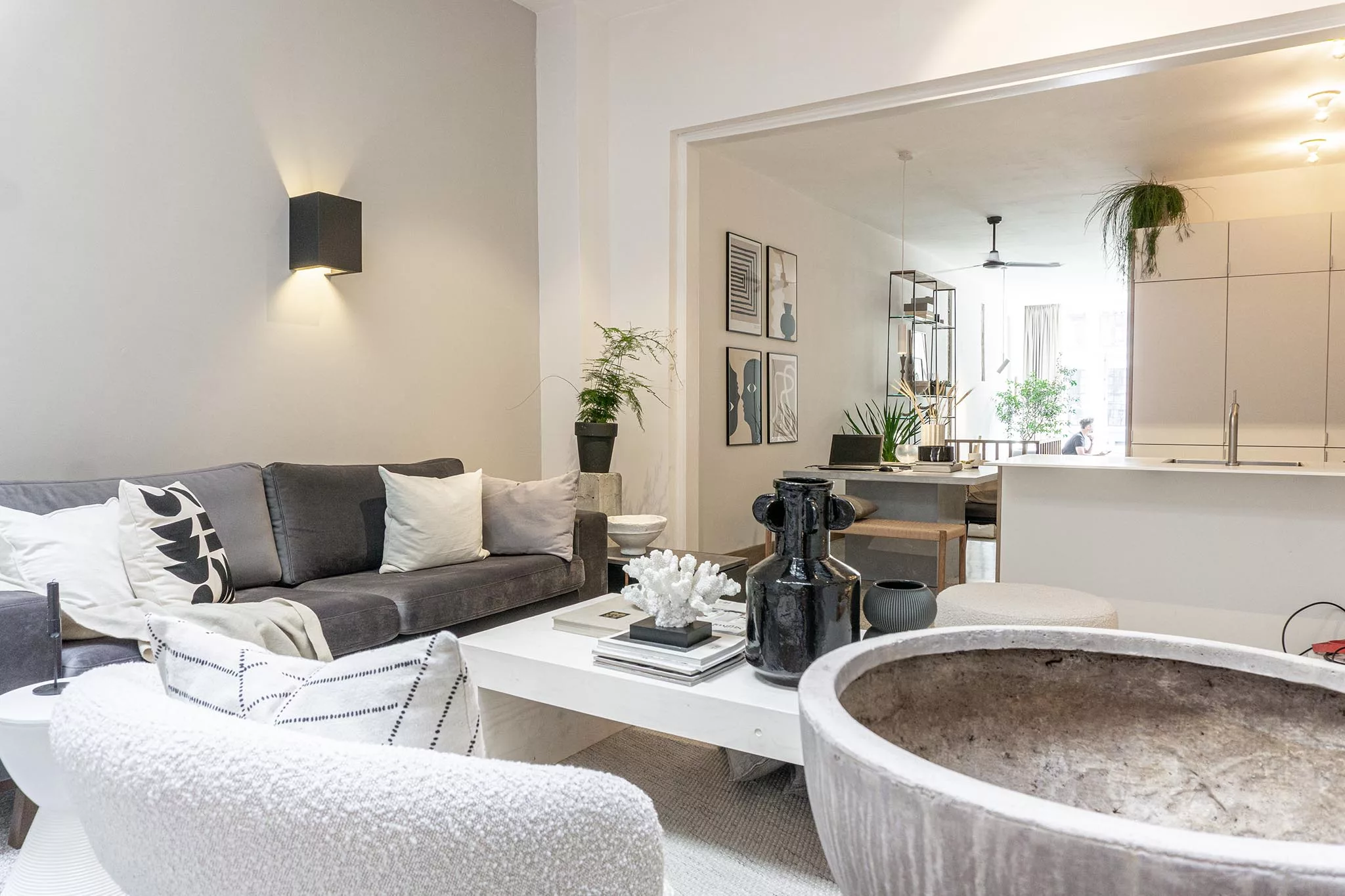 Woonkamer met naturel tinten. De wanden zijn heel licht grijs, de meubels waaronder een bank en stoel zijn grijs en beige. 