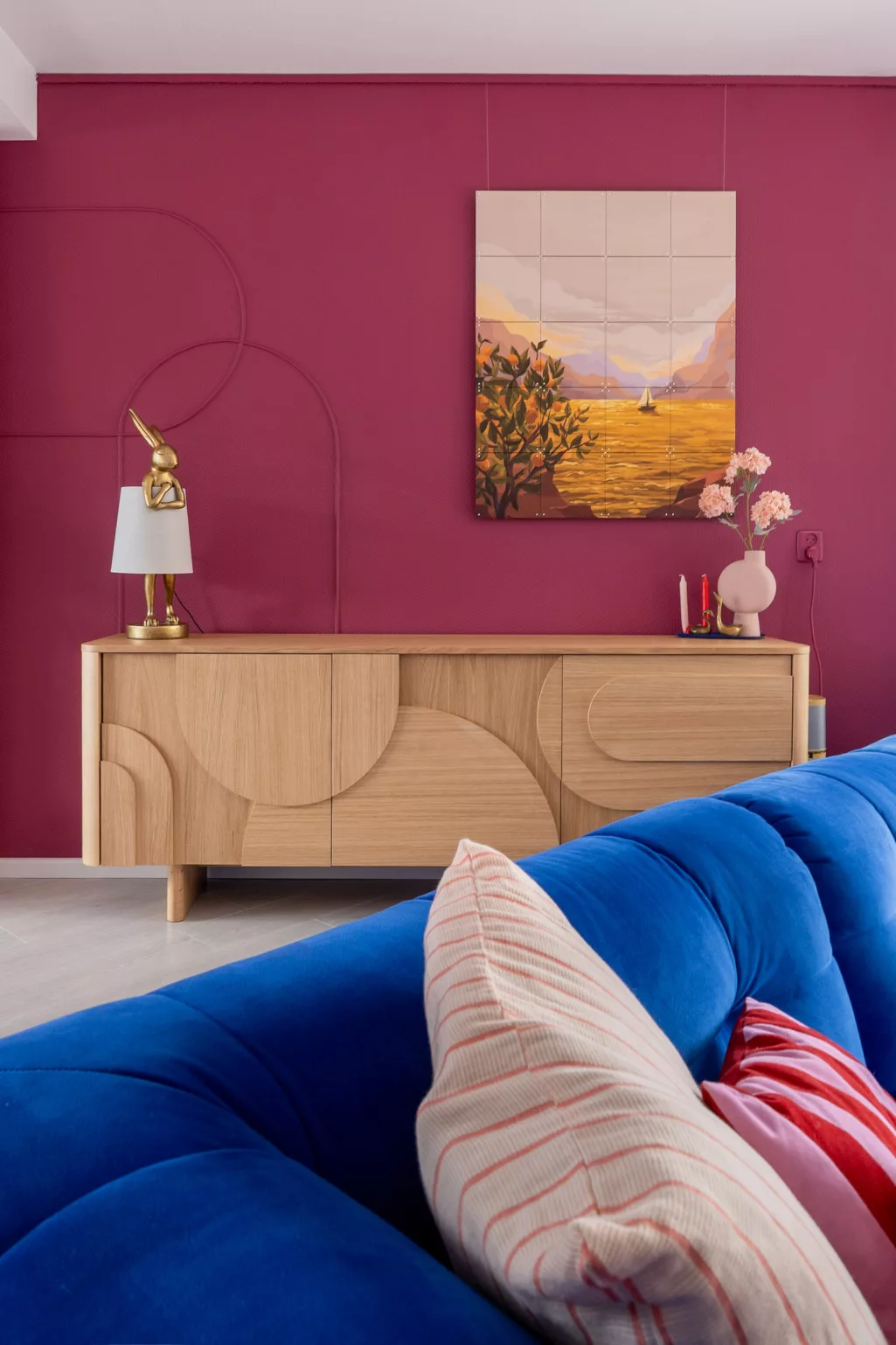 Kleur aubergine op de muur, licht eiken dressoir met ronde vormen en bogen, ixxi landschap warme kleuren. 