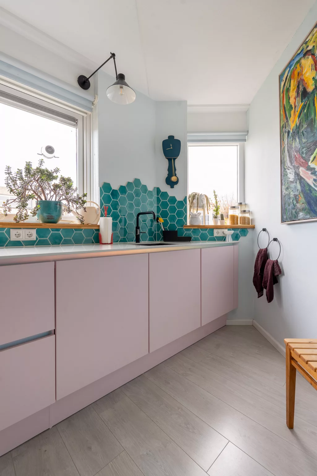 Roze keukenkastjes zonder frontjes, gewrapte fronten, zwarte keukenkraan, zeegroene tegeltjes. 