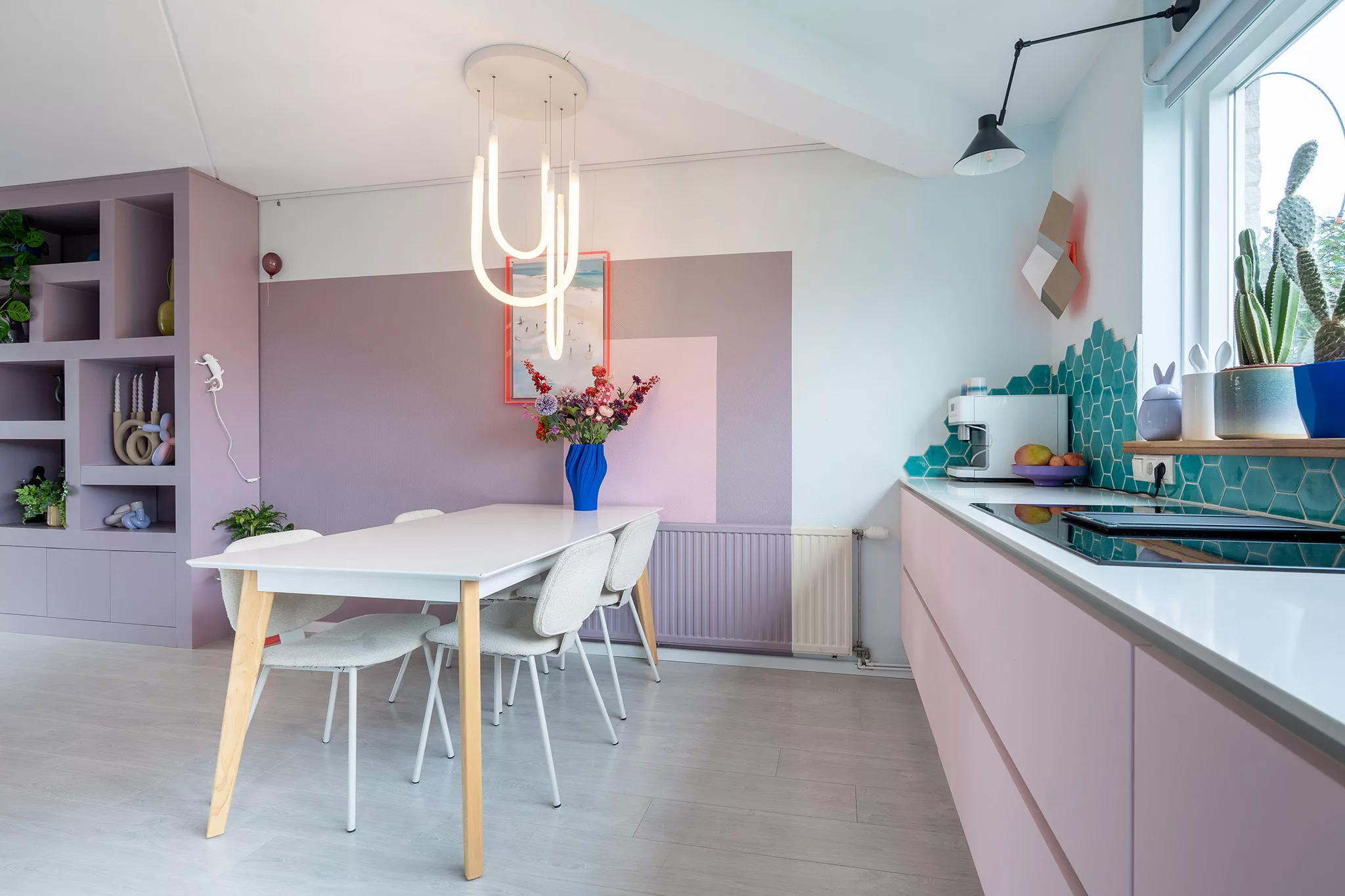 Lila en roze gecombineerd op de muur in vlakken, roze keukenfronten, turquoise hexagoon tegels in speelse vorm. 