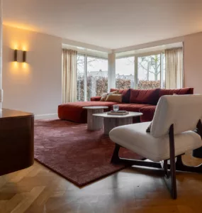 Woonkamer met bordeauxrode lampen, lange ronde wandlampen, groot terrakleurig vloerkleed