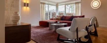 Woonkamer met bordeauxrode lampen, lange ronde wandlampen, groot terrakleurig vloerkleed