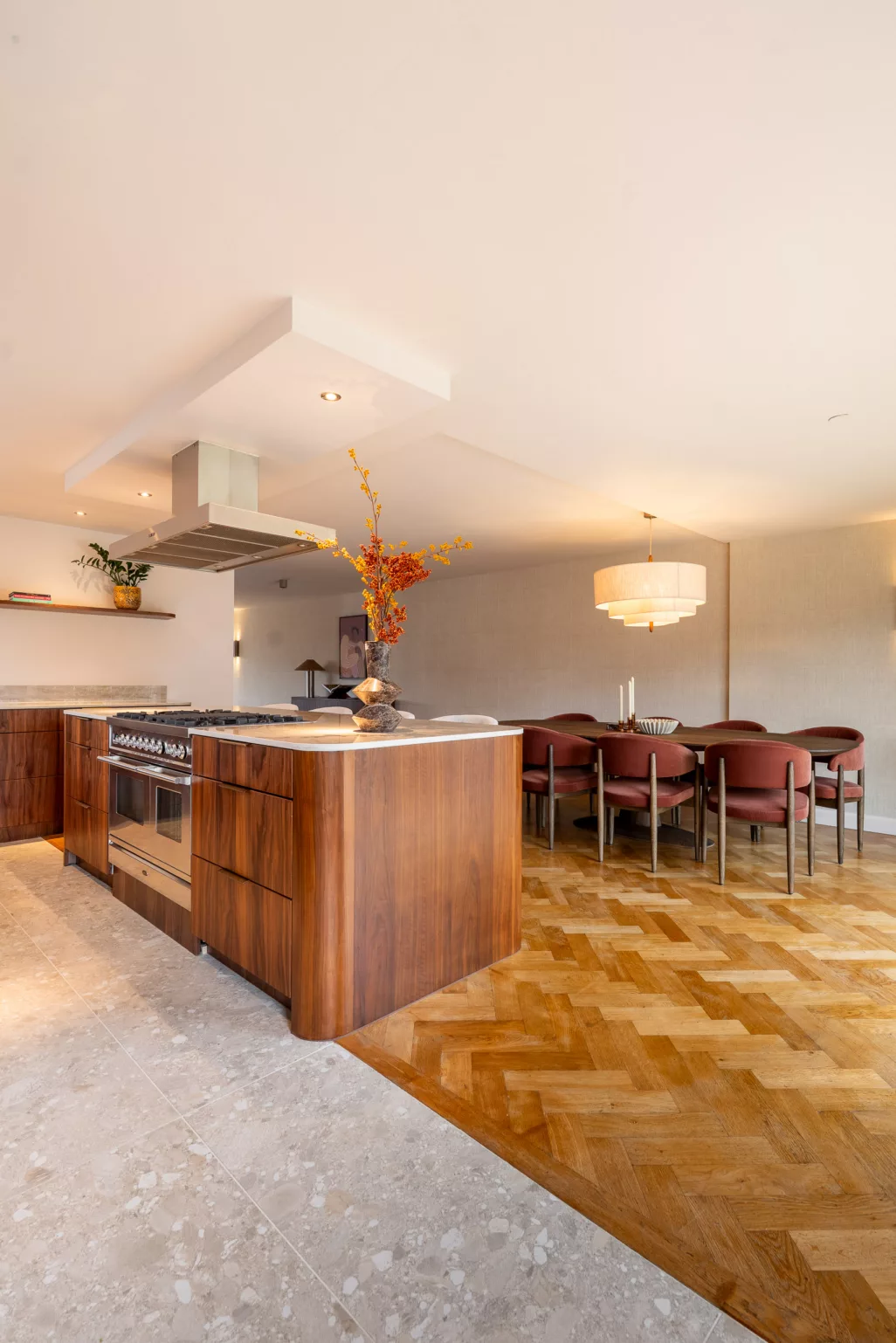 Keuken en woonkamer ineen, walnoot kookeiland, grote eettafel, licht beige blad, afgeronde vormen