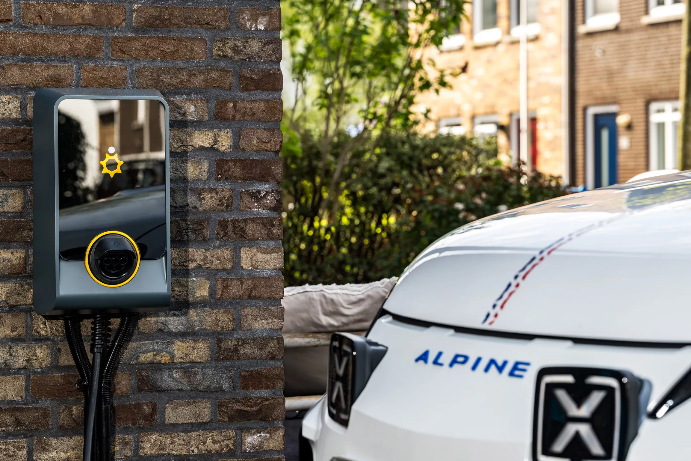 Oprit van een woning, bakstenen muur, laadpaal met auto