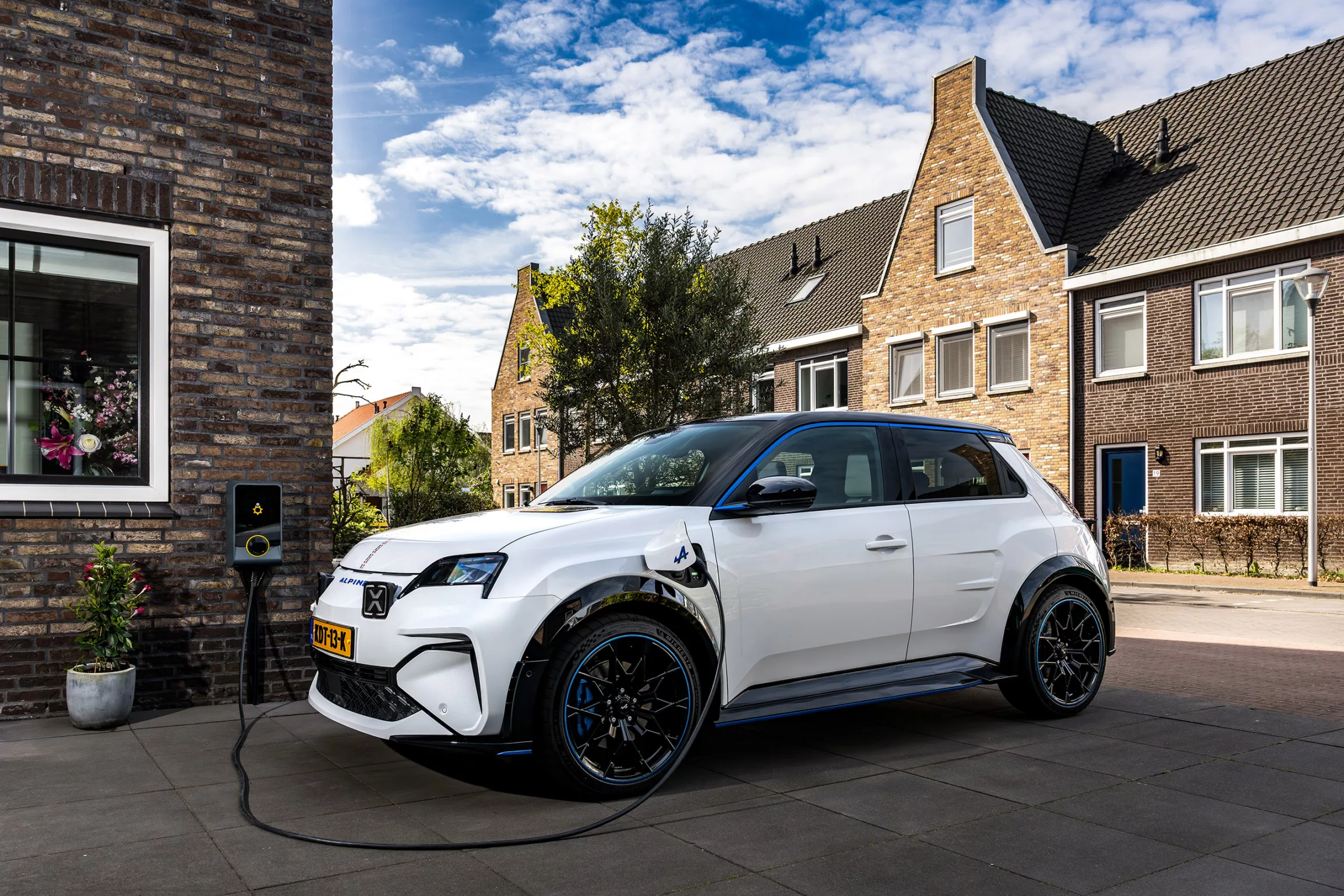 Witte Renault Clio aan laadpaal op de oprit van een nieuwbouwwoning