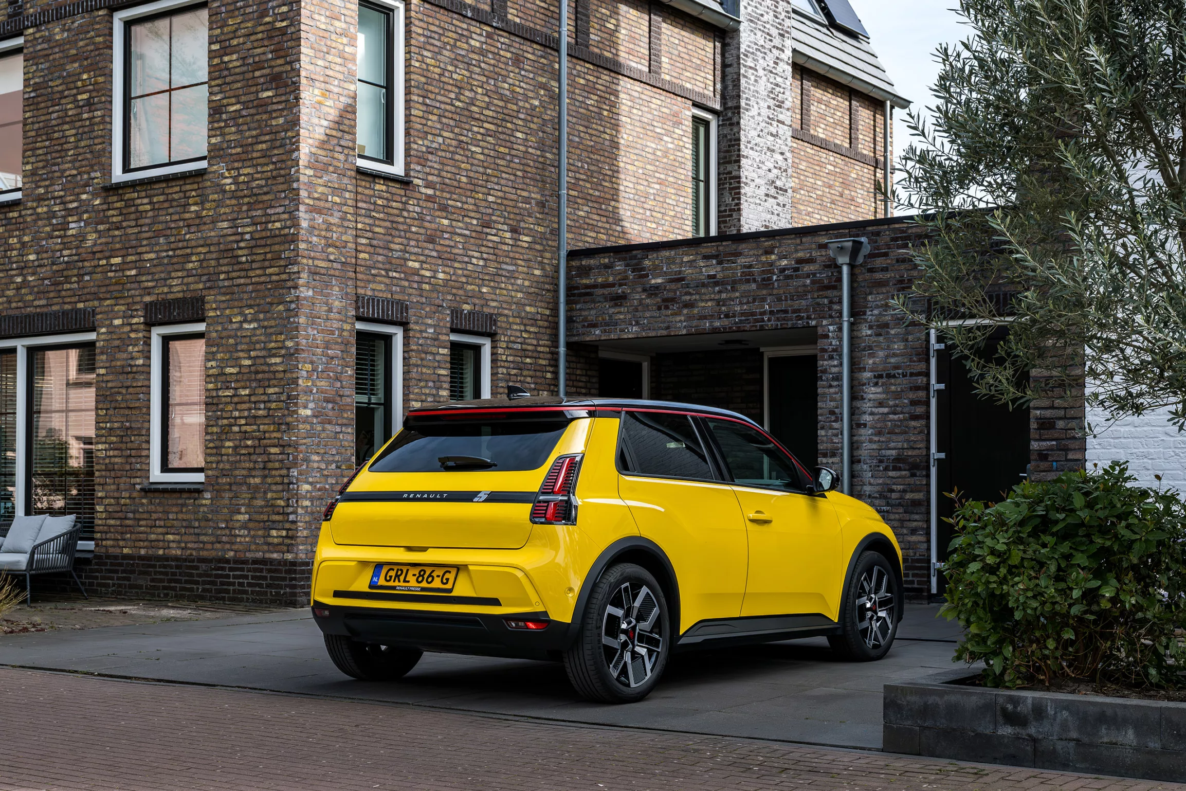 Moderne twee onder 1 kap woning, gebouwd in oude stijl, baksteentjes, auto op rit aan laadpaal 