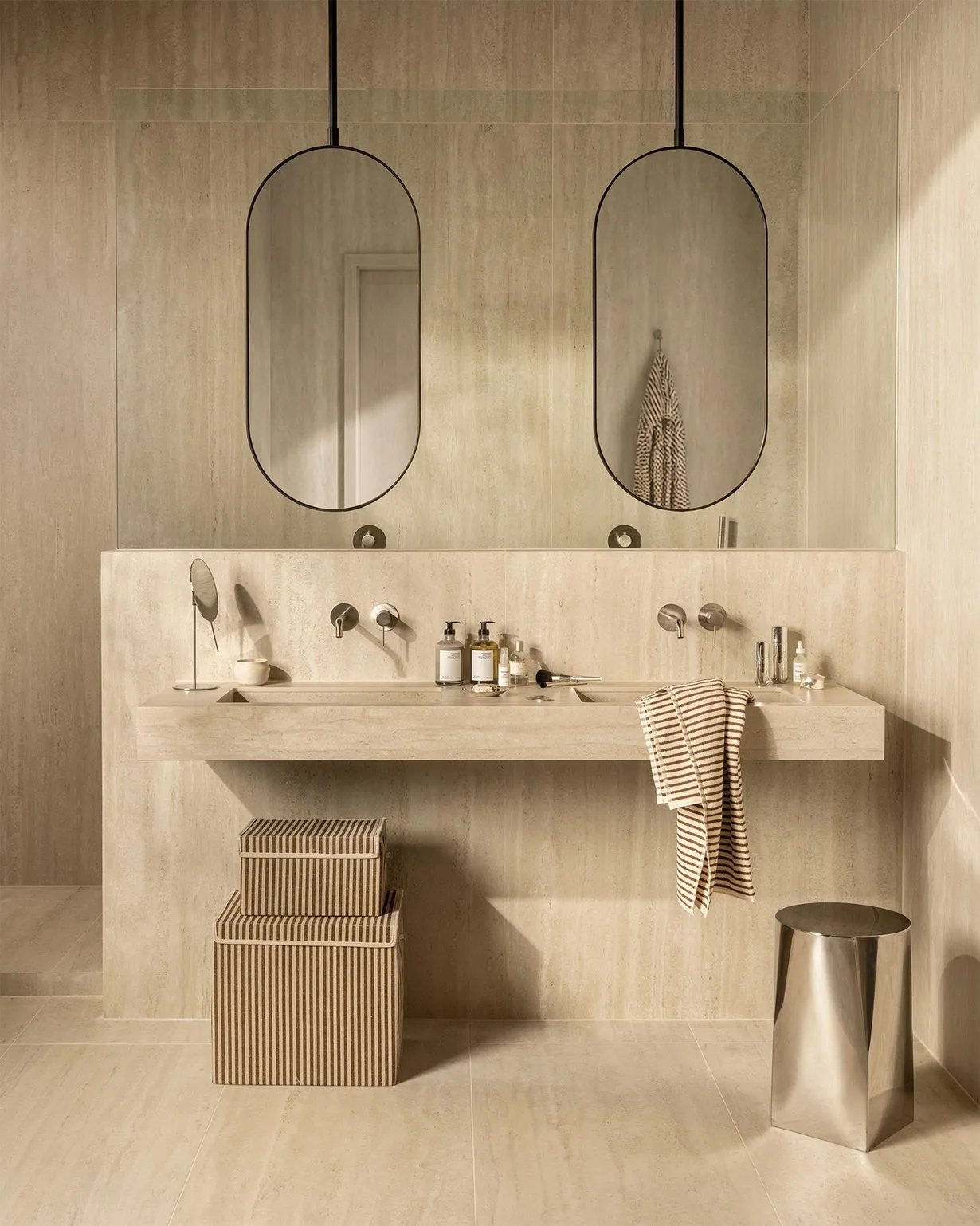 Beige badkamer, volledig betegeld, lange dubbele wastafel, 2 ovalen spiegels.