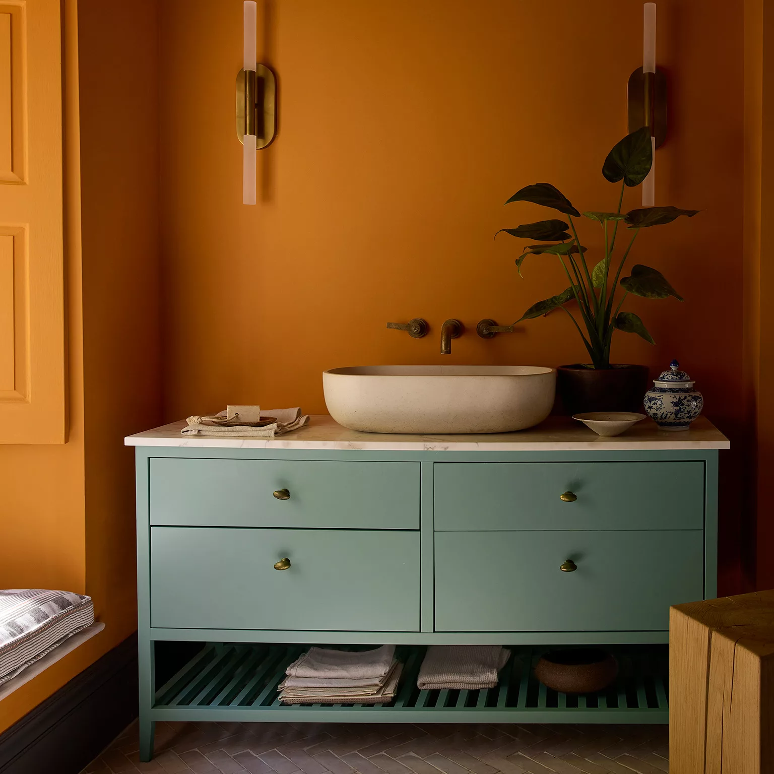 Oranje wanden, patrol kleur wastafelmeubel, witte opzet wasbak