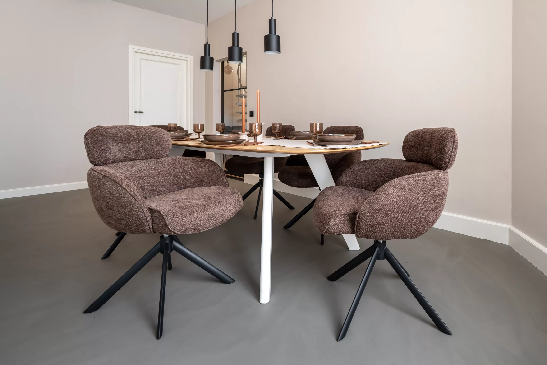 Grijze gietvloer, keuken, bruine eetkamerstoelen met rondingen, rolling fog light op wanden