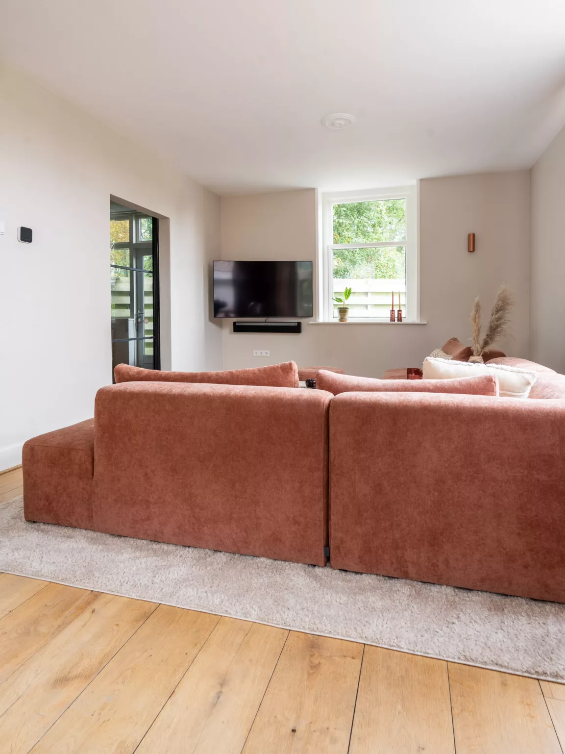Terracotta hoekbank, beige wanden, tv hoek