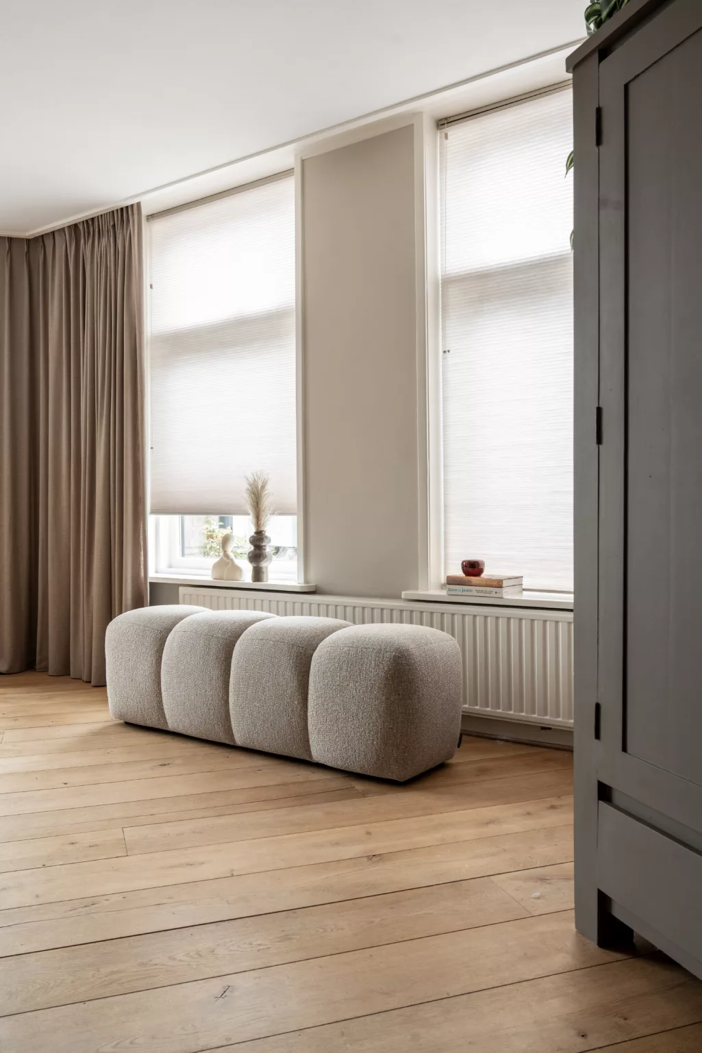 Plissé gordijnen en overgordijnen in naturel tinten, blok bank in beige, vensterbank met accessoires