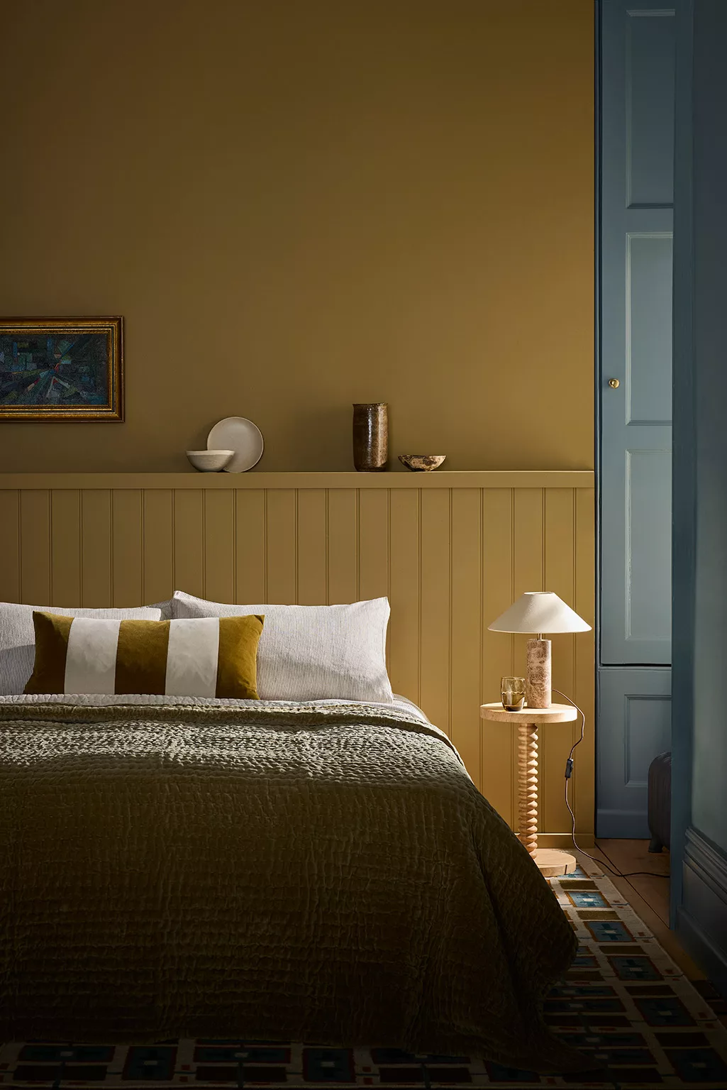 Mostergroene wanden, patrol kleur op deuren, bed met grafisch sprei en kussens